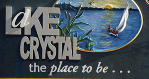 A tractor plows a sunlit field at dawn, creating dust while lush green crops flourish along the edge of the dirt path