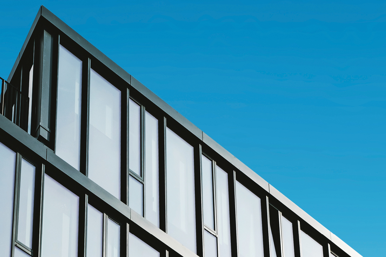 Modern commercial building with a glass and dark metal facade against a clear blue sky